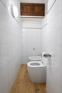 a white bathroom with a toilet and a wooden floor at Casa Camelia in Scarperia +12 photos