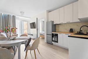 a kitchen and dining room with white cabinets and a table at MDM Apartments in Gdańsk