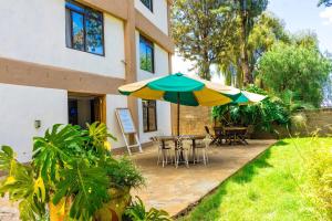 a patio with two umbrellas and a table and chairs at Chic Modern Studio Apartment with Pool in Nanyuki
