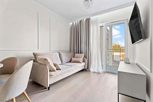a white living room with a couch and a television at MDM Apartments in Gdańsk