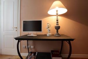 a table with a monitor and a lamp on it at PIO Rooms b&b Parma in Parma
