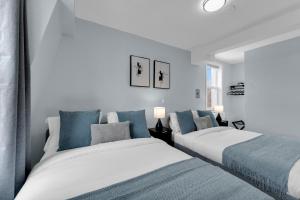 two beds in a room with white and blue at Guestic Hotel at Queen West in Toronto