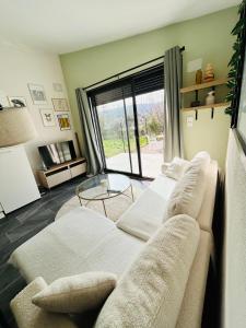 a living room with two couches and a large window at Le Cocon de Laroque in Laroque