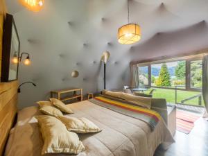 a bedroom with a large bed and a large window at Glamping Vulcanche in Villa Traful