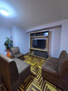 a living room with two couches and a flat screen tv at Candela Apartment PUNO in Puno