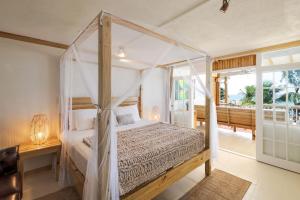 a bedroom with a canopy bed and a balcony at Surfers Bay in Christ Church