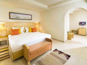a bedroom with a large white bed and a chair at Ksar El Jerid in Tozeur