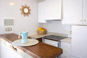 a kitchen with white cabinets and a candle on a counter at EcoHome Menorca in Cala en Porter