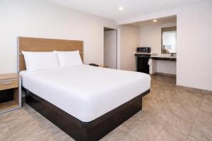 a large white bed in a room with a kitchen at Super 8 by Wyndham Bakersfield CA Near Airport in Bakersfield