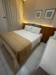 a bedroom with a large bed with white sheets at Apartamento em Resort para família in Barra de São Miguel