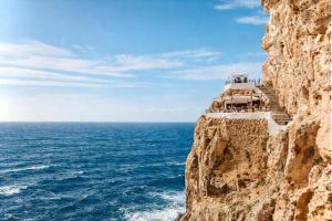 a stairway to the ocean on a cliff at EcoHome Menorca in Cala en Porter +3 photos