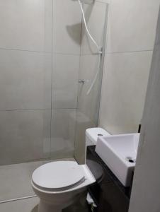 a white bathroom with a toilet and a sink at Hotel Linassi in Cruz Alta