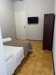 a bedroom with two beds and a flat screen tv at Hotel Linassi in Cruz Alta