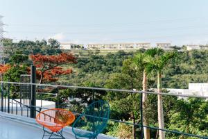 two chairs on a balcony with a view of trees at Spice Motel Okinawa in Kitanakagusuku