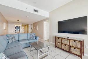 a living room with a blue couch and a tv at Phoenix I 1142 in Orange Beach