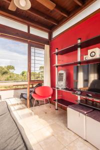 a kitchen with a red wall and a red chair at Cabañas Cambados in Villa Gesell +31 photos