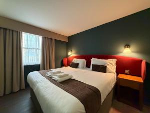 a bedroom with a large bed with a red headboard at HNFC Stays - Harmony Accommodation in Elswick