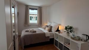 a white bedroom with a bed and a window at Garden Rooms near Munich in Althegnenberg