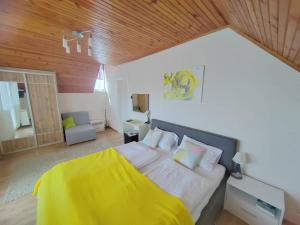 a bedroom with a large bed with a yellow blanket at Maja Anna Vendégház in Bogács