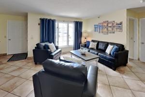 a living room with black leather couches and a table at Put-in-Bay Poolview Condo #2 in Put-in-Bay