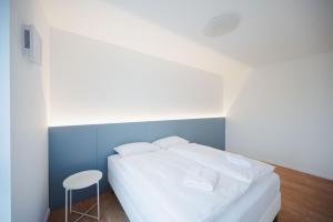 a bedroom with a white bed and a stool at Castle view Vinetto apartment with free parking in Trenčín
