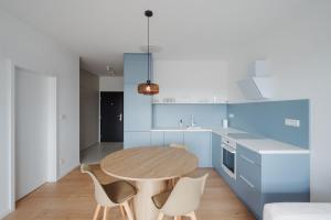 a kitchen with blue cabinets and a wooden table and chairs at Castle view Vinetto apartment with free parking in Trenčín