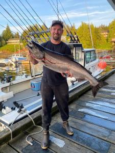 a man holding a large fish in front of a boat at Rudolph's Reindeer Den in Ketchikan