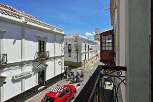 a red car parked on a city street with buildings at Colors House in Sucre