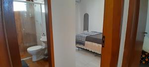 a bathroom with a toilet and a bed in a room at Suíte aconchego in Guaratuba +16 photos