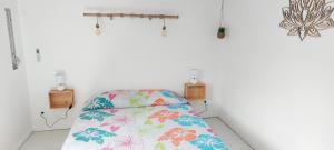 a white room with a bed with a colorful blanket at Ti Cactus Guadeloupe in Sainte-Rose