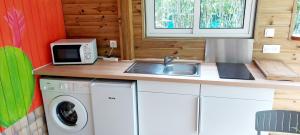 a kitchen with a washing machine and a microwave at Ti Cactus Guadeloupe in Sainte-Rose