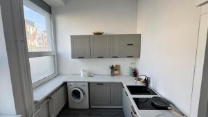 a white kitchen with a washing machine and a window at atelier in Bratislava +5 photos