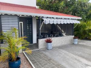 a house with awning and a patio with plants at Gîte T2 cosy indépendant tout confort in Vieux-Fort
