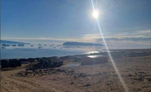 a sun shining over a body of water with houses at Tent in ices in Nibe