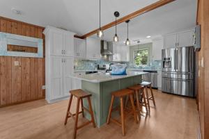 a kitchen with white cabinets and a large island with bar stools at 2444 - Sea Forever in Duck