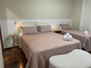 zwei Betten in einem Hotelzimmer mit Handtüchern darauf in der Unterkunft Flow Pousada in Maringá