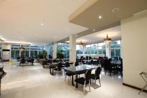 a dining room with tables and chairs and windows at The Oriental Hotel Legazpi in Legazpi