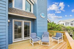 a blue house with two chairs on a deck at 3979 - Wright by the Coast in Duck +52 photos
