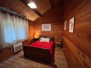 a bedroom with a red bed in a wooden room at écrin d'éveil in Campagne-lès-Guînes