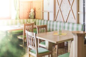a restaurant with wooden tables and green chairs at Almhotel Lenz in Valdaora