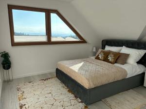 a bedroom with a bed with a large window at Glamoon Mountain Apartment with Jacuzzi and Sauna, Nowy Targ in Nowy Targ +18 photos