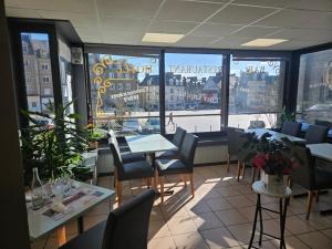 a restaurant with tables and chairs and a large window at Hotel le Saint Germain in Flers