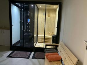 a large glass shower in a room with a bench and a chair at Glamoon Mountain Apartment with Jacuzzi and Sauna, Nowy Targ in Nowy Targ