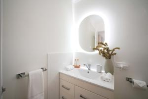 a white bathroom with a sink and a mirror at Oceanview Beach Shack with Pool & Walk to Dining in Aldinga Beach