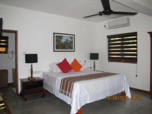 a bedroom with a bed with orange pillows on it at Zee's Garden in Matale