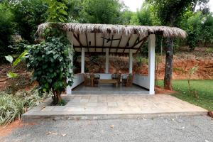 cenador con sillas y mesa con techo en Zee's Garden, en Matale