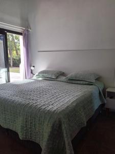 a bedroom with a bed with a green comforter and a window at Kilua in Punta del Este +10 photos