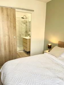 a bedroom with a large white bed and a bathroom at La Dolce Loca in Orange