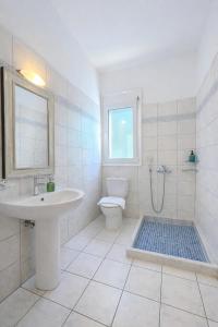 a white bathroom with a sink and a toilet at Villa Lefka Stunning Seaside Villa in Corfu with Private Gardens in Melíkia +35 photos