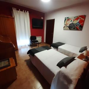 a hotel room with two beds and a television at Alojamiento Peña Dorada in Lumpiaque
